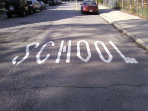 The word SCHOOL painted across a residential street